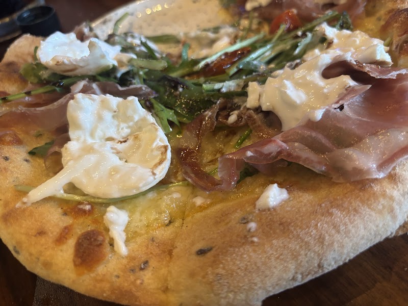 Close-up of Di Martina's signature artisan pizza with prosciutto and burrata
